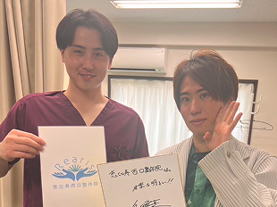 左手を顔の位置に上げた飯田祐基さん