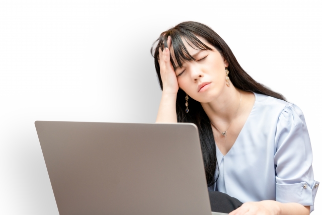 疲れた女性が頭に手を置く 疲れを感じて目を閉じている