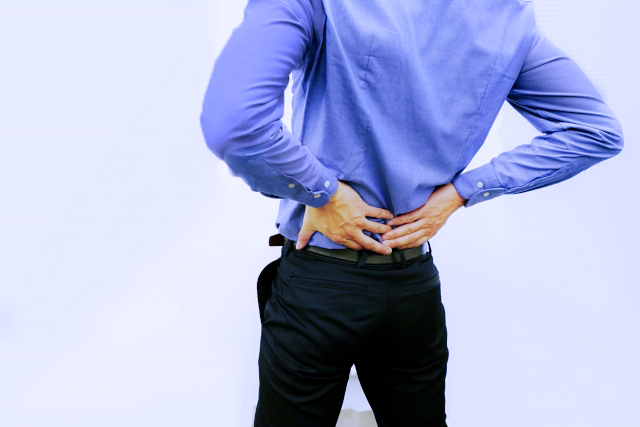 腰痛を解消するためそりかえる運動をする 腰を押さえて反っている