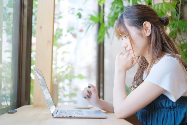 窓際の机でパソコンを使う